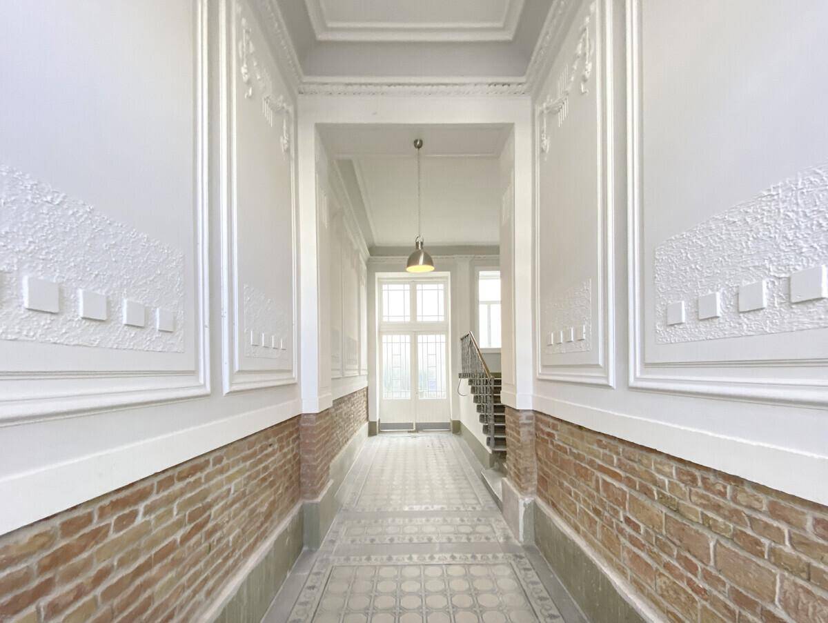 Langer Flur mit hohen Decken, Stuckverzierungen und gemustertem Fliesenboden.