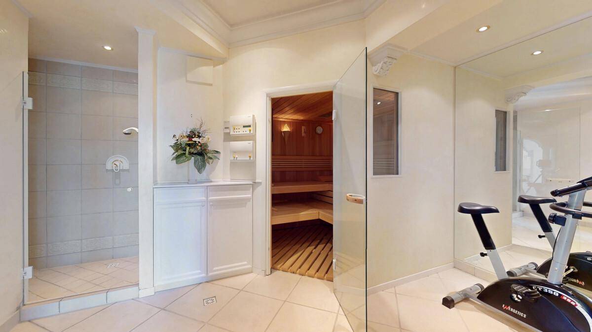 Privater Fitnessraum mit Sauna, Dusche und Trainingsgeräten.