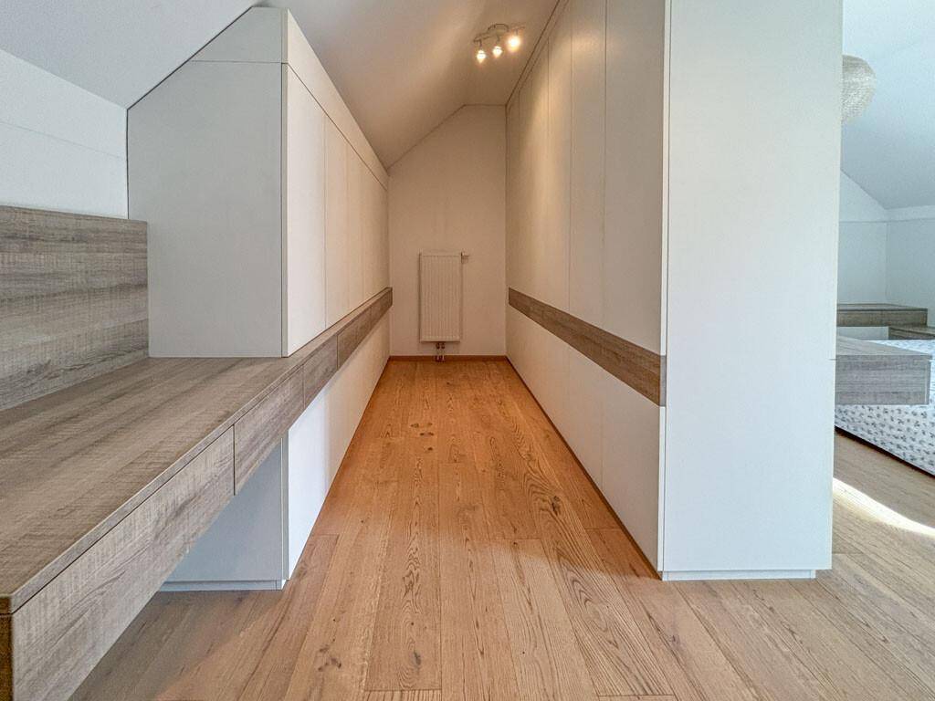 Begehbarer Kleiderschrank mit maßgefertigten Einbauschränken und Holzboden im Schlafzimmer.