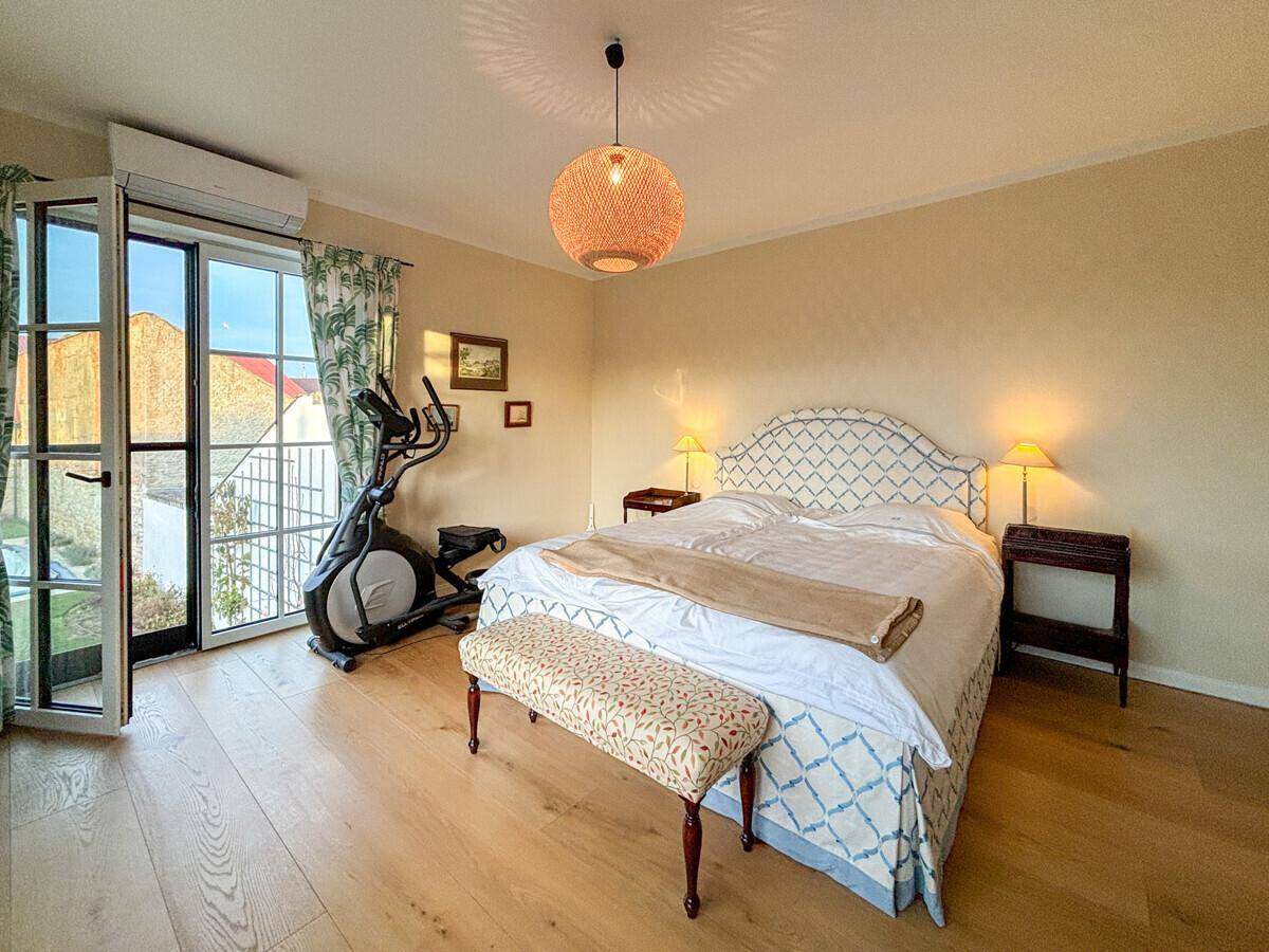 Helles Schlafzimmer mit Doppelbett, Trainingsgerät und direktem Zugang zu einem Balkon.