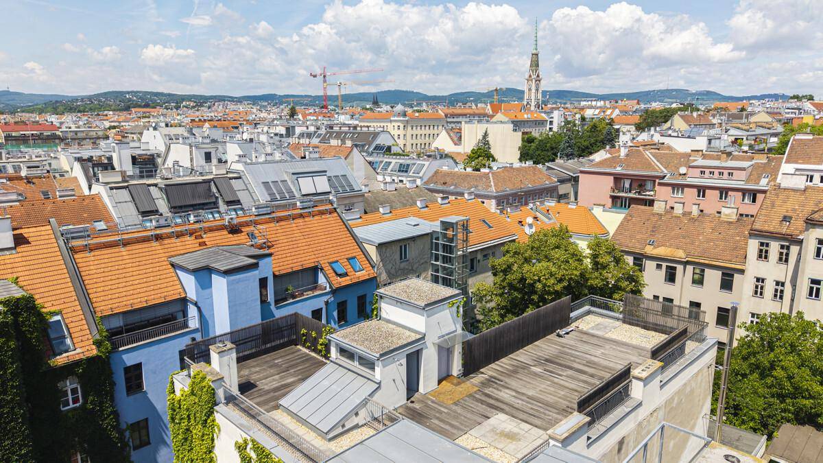 Panoramablick über die Dächer der Stadt mit historischer Architektur und grünen Akzenten.