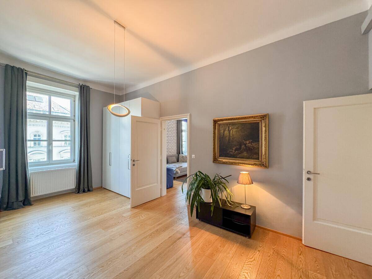 Geräumiges Wohnzimmer mit Holzboden, hohen Decken und Blick auf die Stadt.