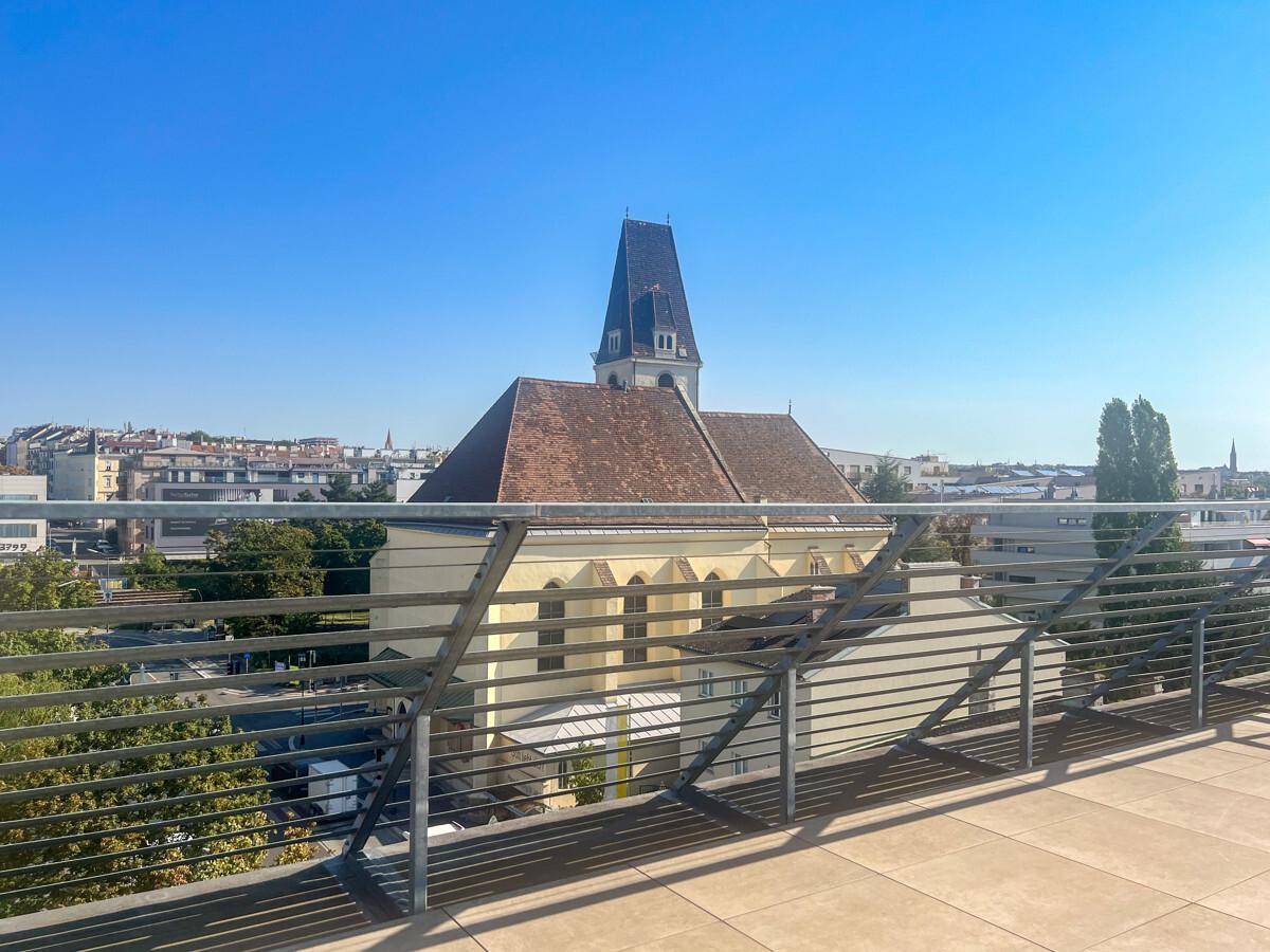 Dachterrasse mit weitem Blick über die Stadt und eine historische Kirche.