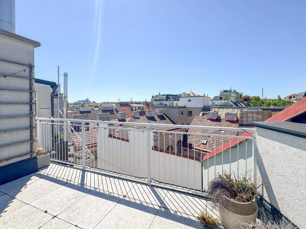 Weitläufige Dachterrasse mit Panoramablick über die Dächer der Stadt unter blauem Himmel.