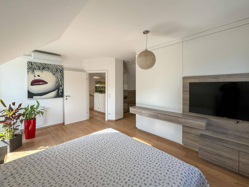 Geräumiges Schlafzimmer mit Holzboden, TV-Möbel und moderner Kunst an der Wand.