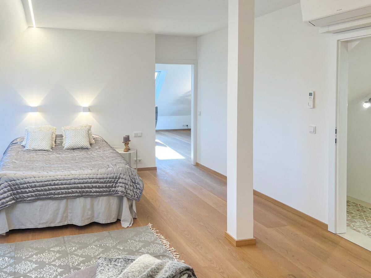 Gemütliches Schlafzimmer mit Holzboden, Doppelbett und Zugang zu einem weiteren Raum.
