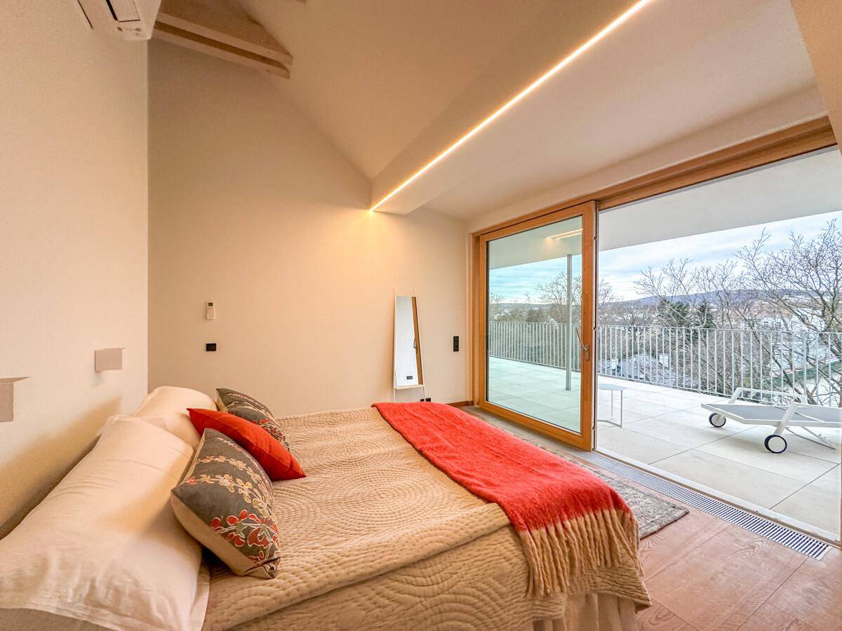 Schlafzimmer mit großen Schiebetüren, die auf eine private Dachterrasse führen, und Holzboden.