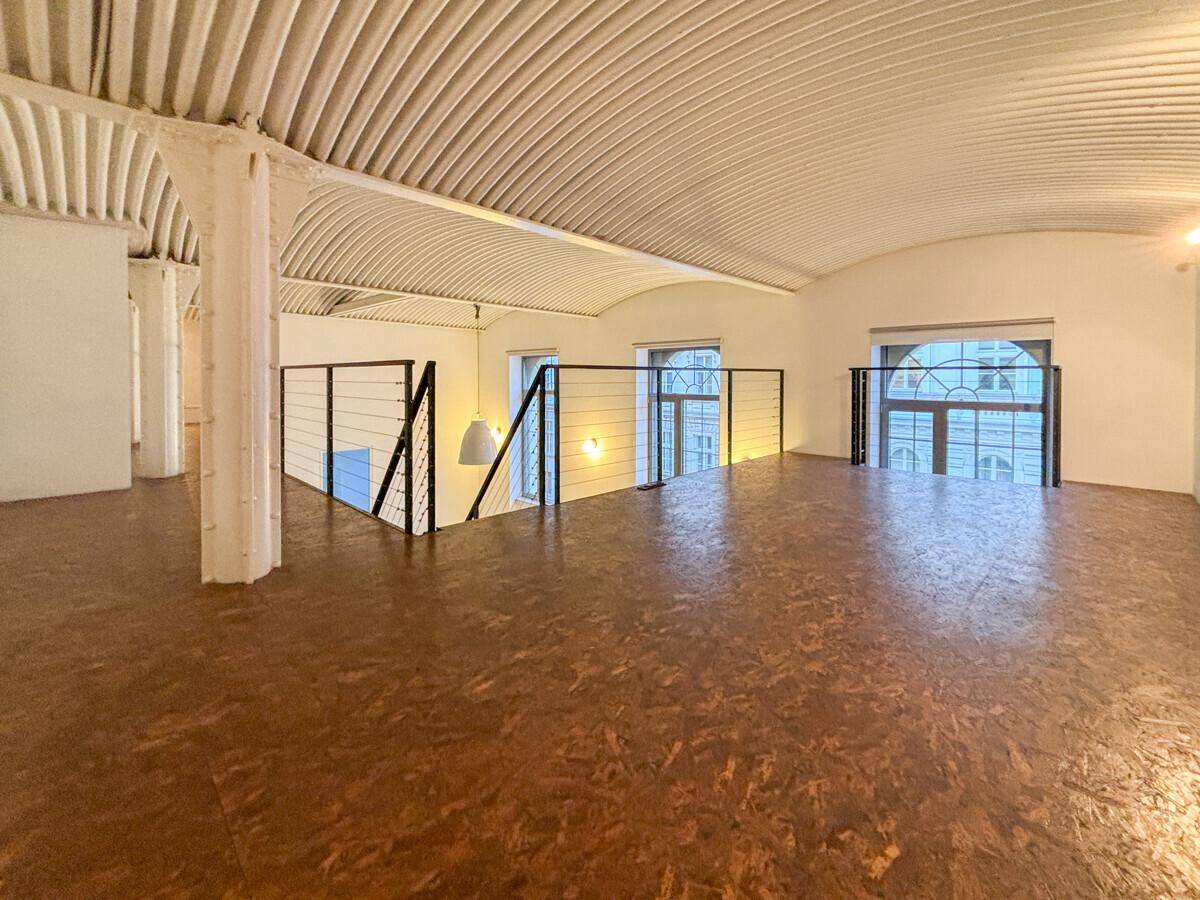 Galeriebereich im Loft mit Holzboden und Blick auf die hohen Fenster.