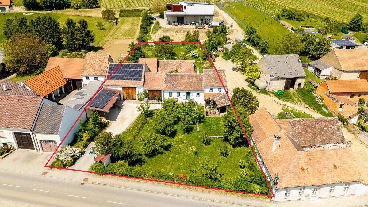 Luftaufnahme eines charmanten Anwesens mit großem Garten, Photovoltaikanlage und Blick auf die umliegende Landschaft und Weinberge.
