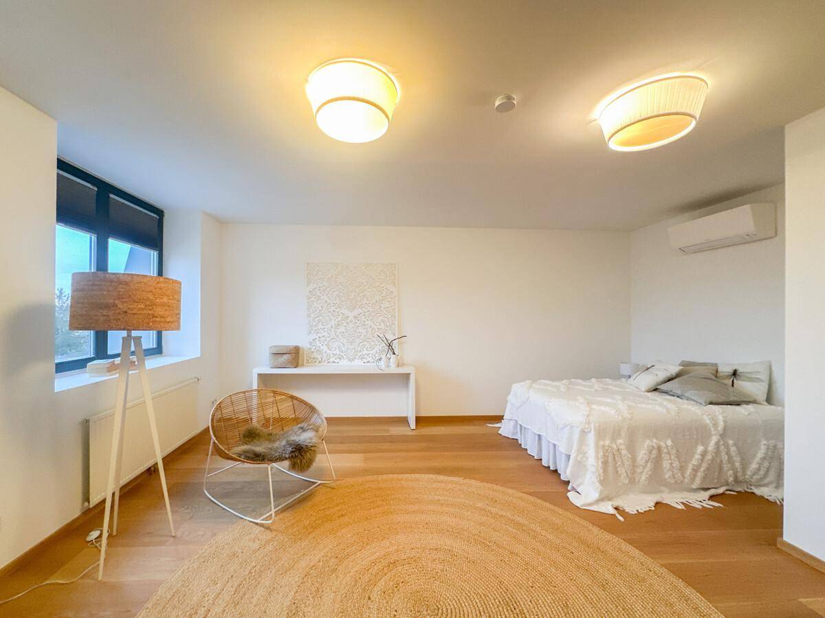 Geräumiges Schlafzimmer mit Holzboden, Klimaanlage und modernen Leuchten.