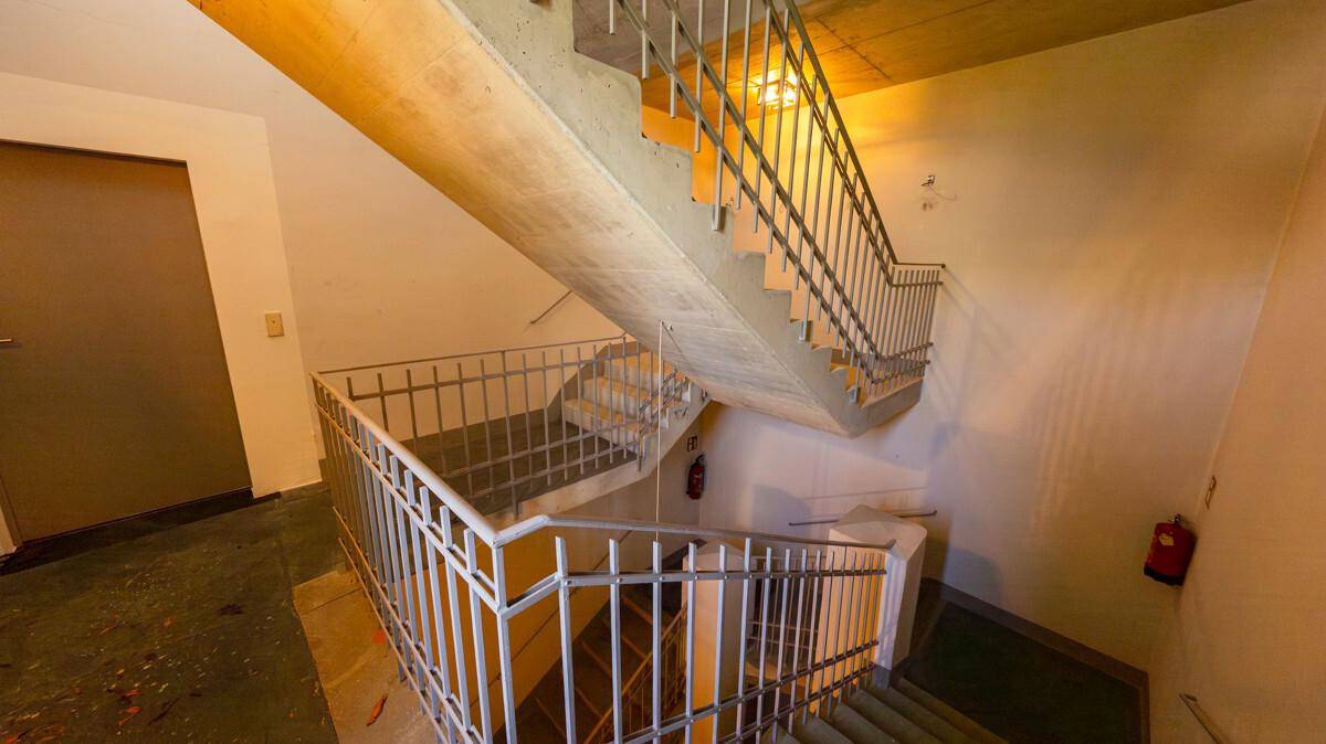 Treppenhaus mit Betonstufen und Metallgeländer, das die verschiedenen Etagen des Gebäudes verbindet.