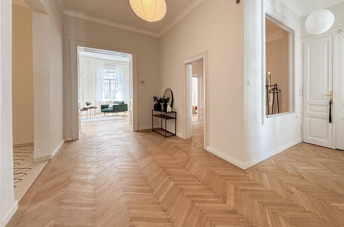 Geräumiger Flur mit Fischgrätparkett, hohen Decken und Zugang zu verschiedenen Räumen.