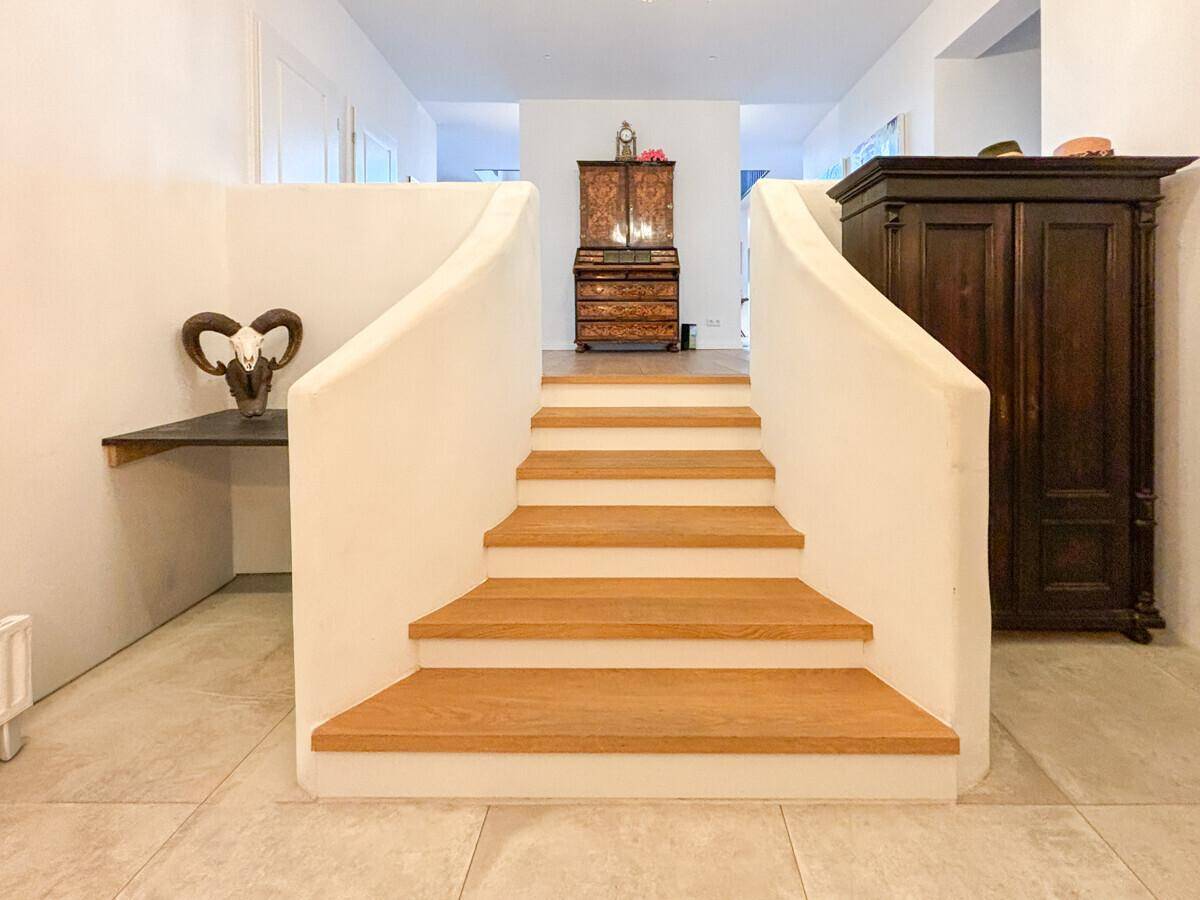 Eingangsbereich mit eleganter Holztreppe und traditionellen Möbeln, die eine einladende Atmosphäre schaffen.