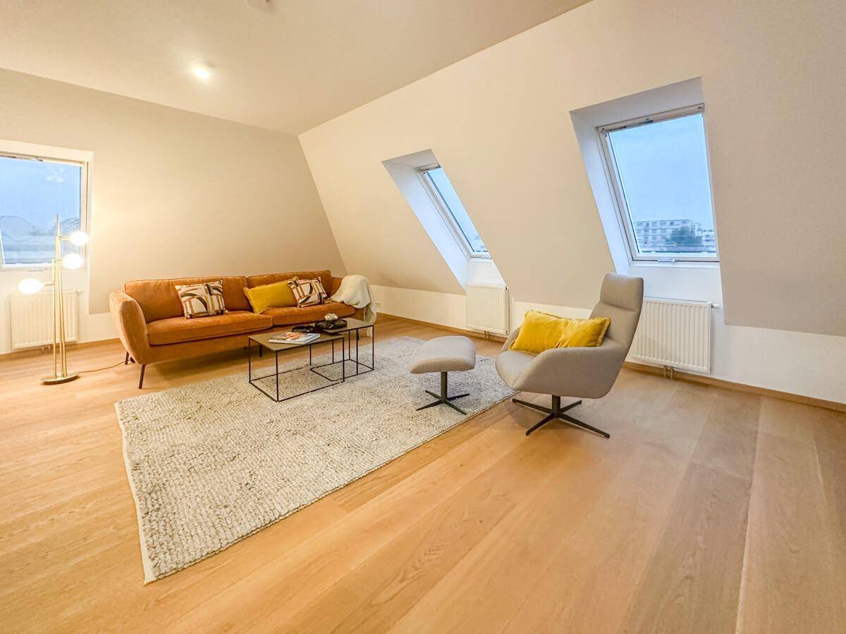 Gemütliches Wohnzimmer im Dachgeschoss mit schrägen Wänden, Dachfenstern und Holzboden.