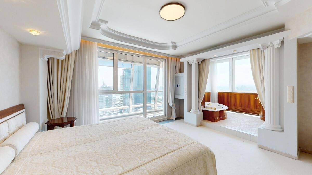 Luxuriöses Schlafzimmer mit Doppelbett, hohen Decken und integriertem Whirlpool.