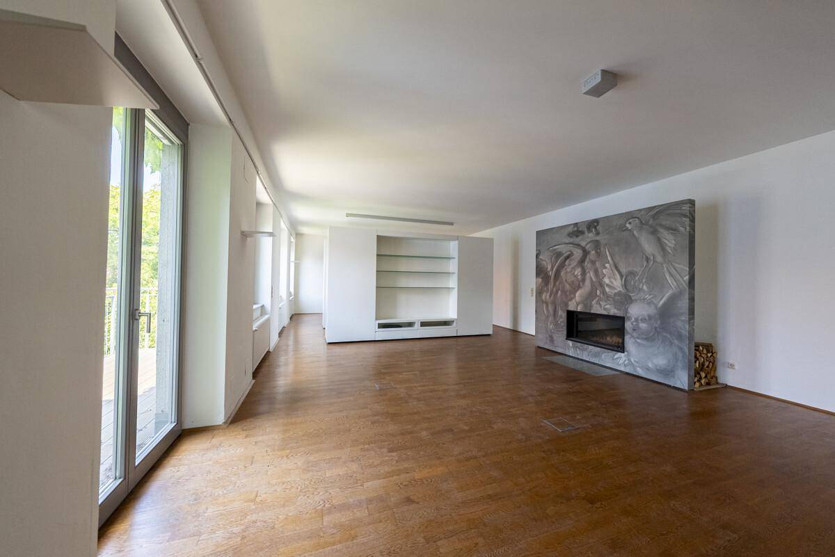 Großzügiges Wohnzimmer mit Holzboden, dekorativem Kamin und großen Fenstern für viel Tageslicht.