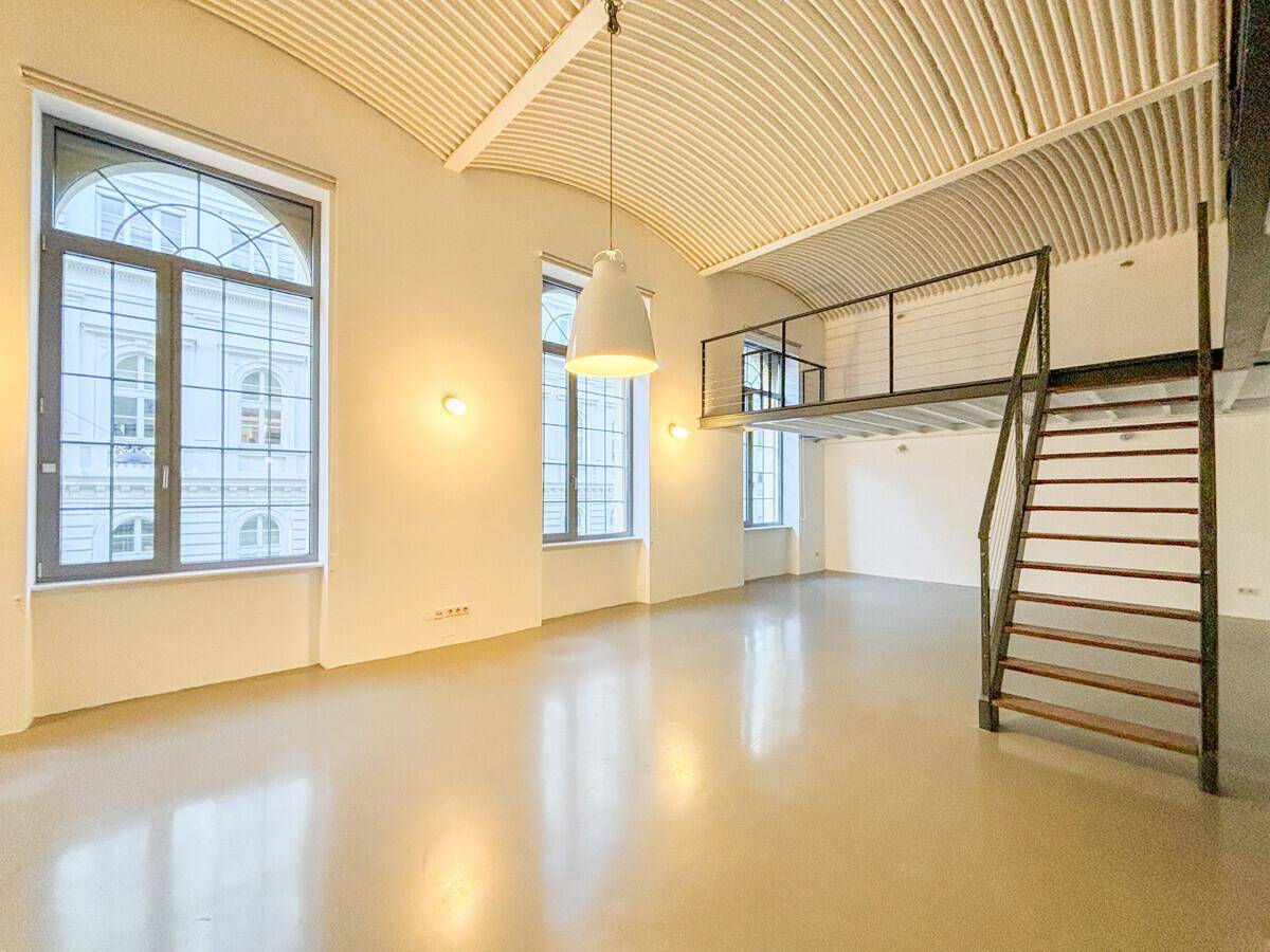 Weitläufiger Loft-Raum mit hohen Bogenfenstern, gewölbter Decke und Galerie.