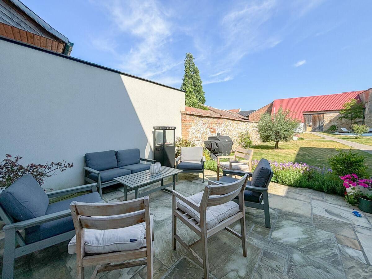 Gemütliche Terrasse mit modernen Gartenmöbeln, Grillbereich und Blick auf den weitläufigen Garten.