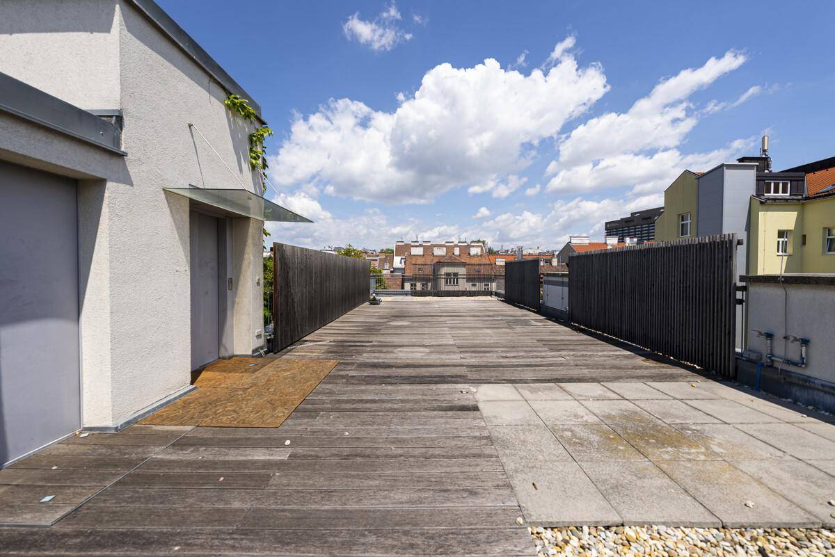 Geräumige Dachterrasse mit Holzboden und Stadtblick, ideal für Entspannung im Freien.