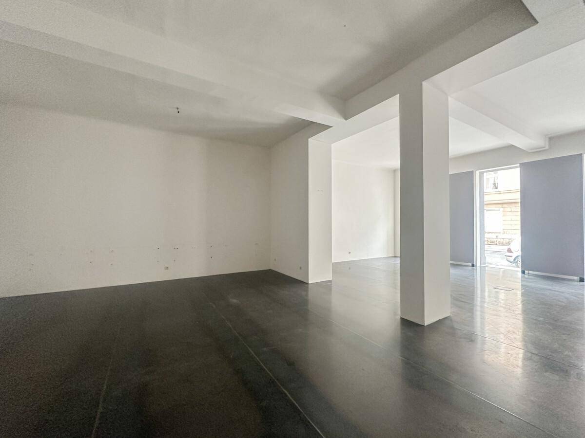 Leerer, heller Raum mit weißen Wänden, Säulen und glänzendem Betonboden, ideal für gewerbliche Nutzung.