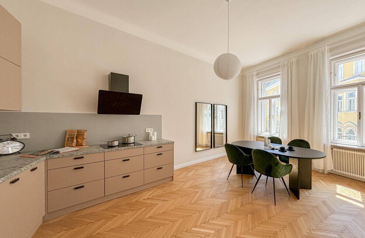 Moderne Küche mit beigefarbenen Schränken, Granitarbeitsplatte und Essbereich.