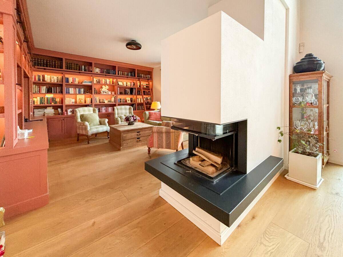 Modern gestalteter Kamin im Wohnzimmer, umgeben von hellem Eichenparkett, schafft eine stilvolle Wärme.