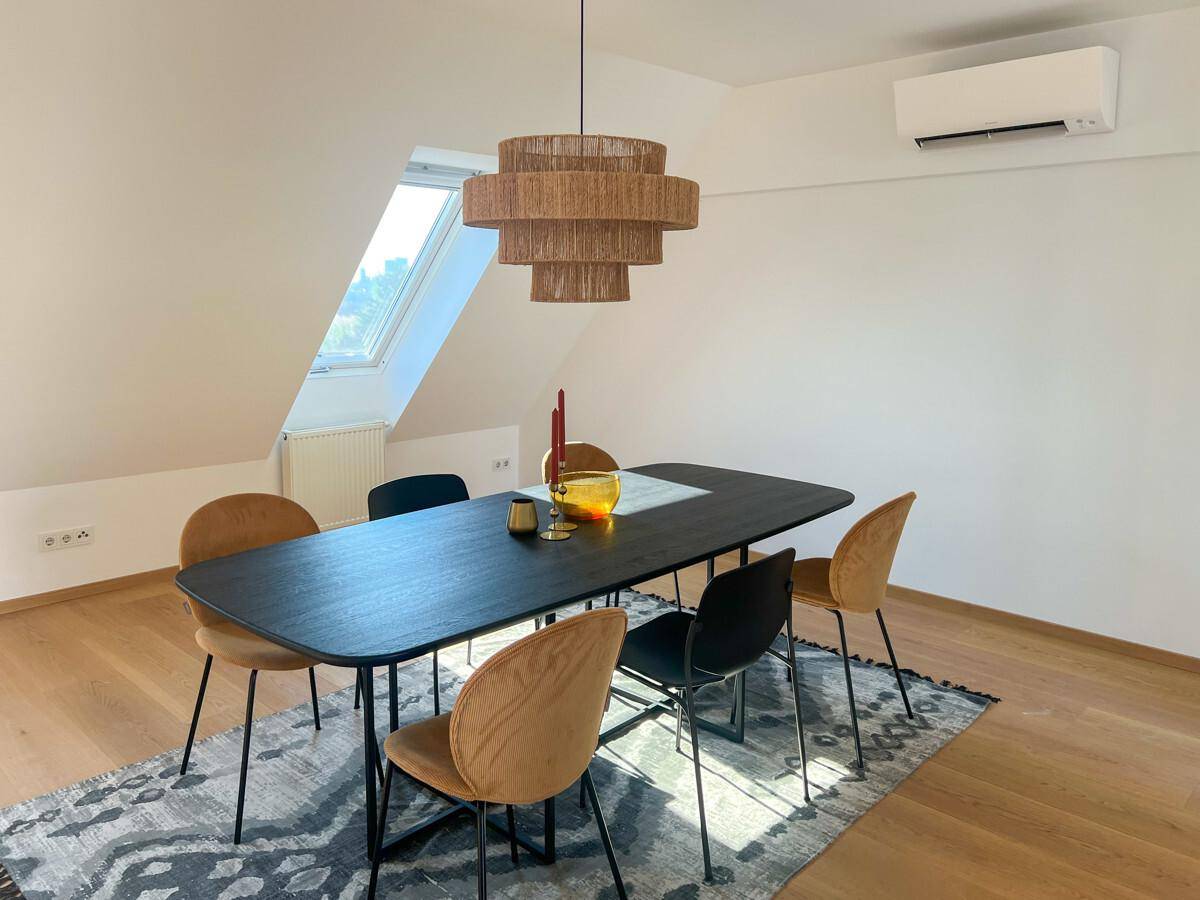 Moderner Essbereich im Dachgeschoss mit großem Tisch, stilvollen Stühlen und Holzboden.