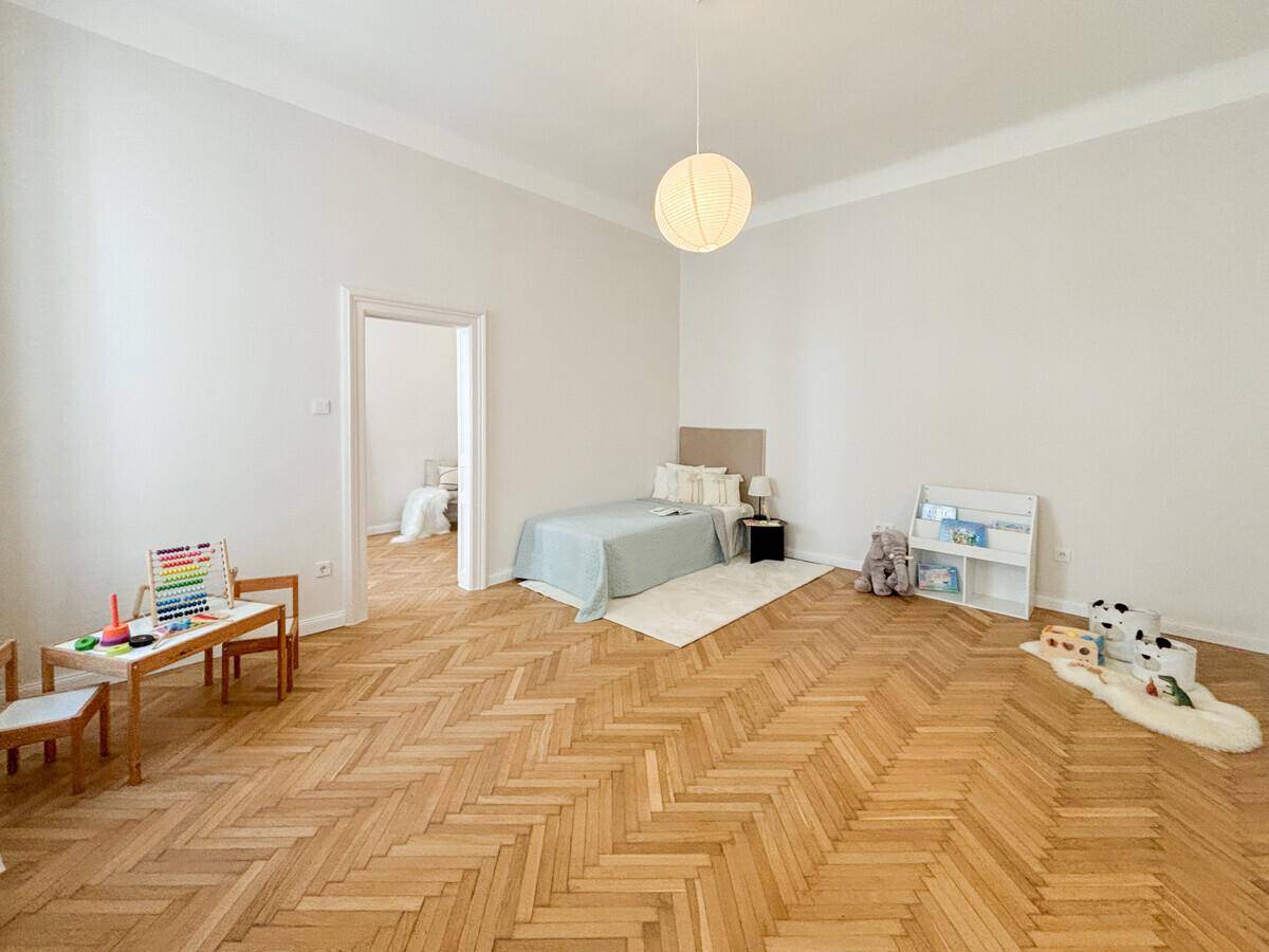 Kinderzimmer oder Gästezimmer mit Fischgrätparkett, hellem Ambiente und Spielbereich.