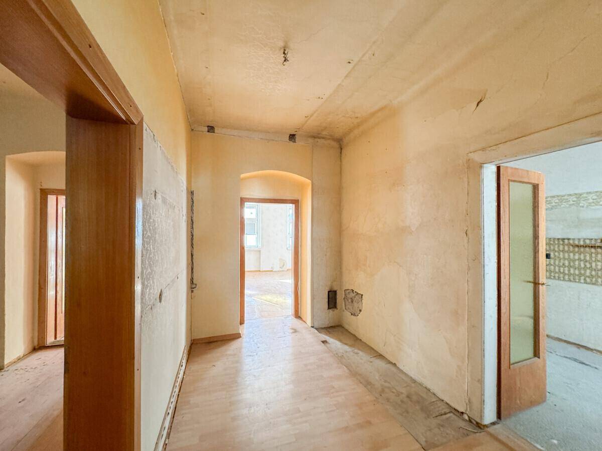 Ein Flur in einem Altbau mit sichtbaren Abnutzungsspuren, der eine Renovierung benötigt.