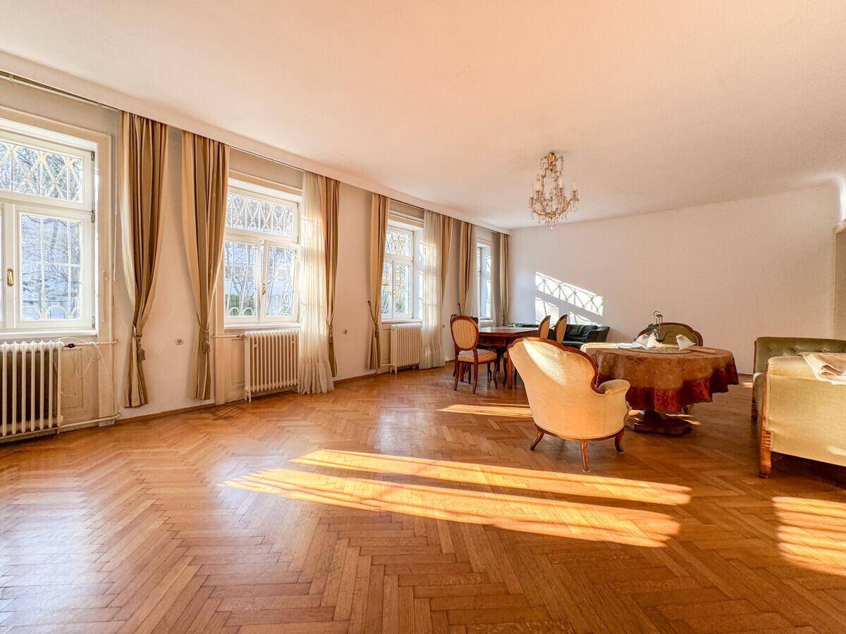 Lichtdurchfluteter Wohn-Essbereich mit elegantem Fischgrätparkett und viel Tageslicht.