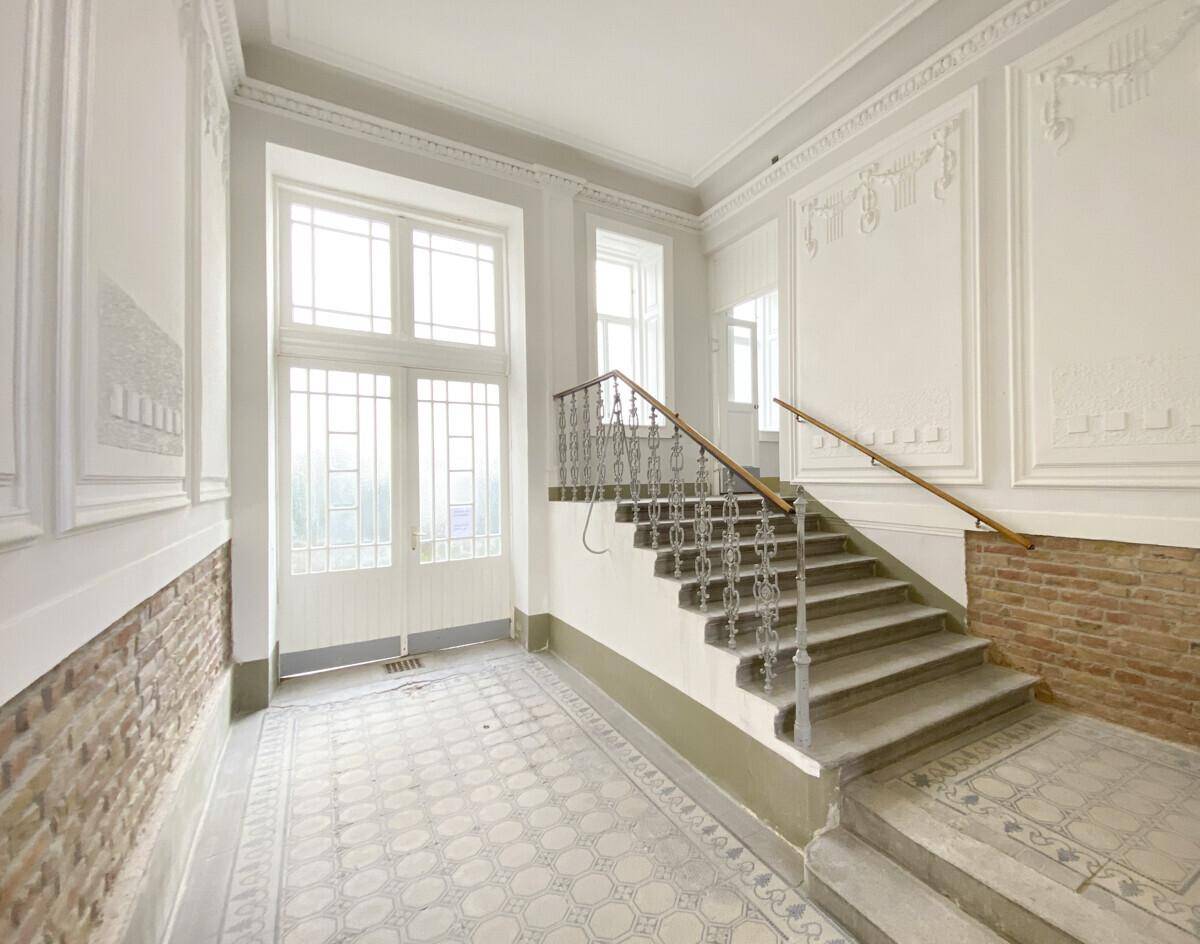 Repräsentativer Eingangsbereich mit hohen Decken, Stuckelementen und historischem Fliesenboden.