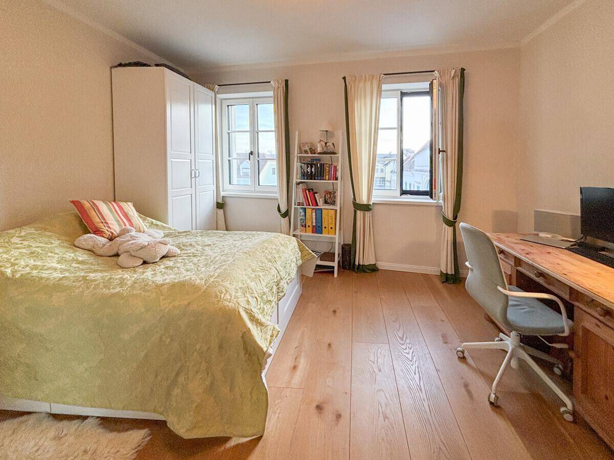 Helles Schlafzimmer mit Einzelbett, weißem Kleiderschrank und Holzboden.