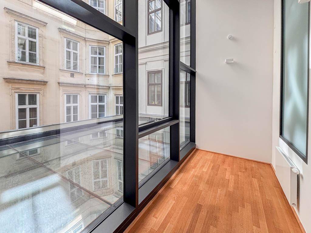 Heller Büroraum mit großen Glasfenstern, die einen Blick auf die umliegenden Gebäude ermöglichen.
