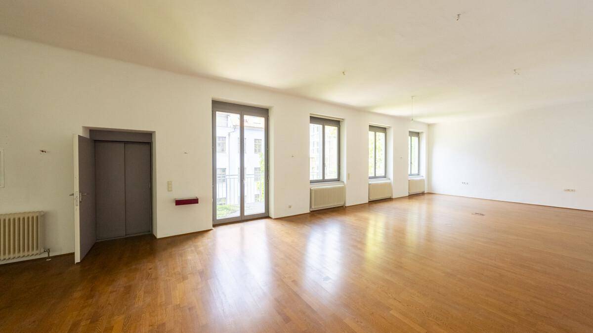 Helles und geräumiges Wohnzimmer mit Holzboden, großen Fenstern und direktem Zugang zum Aufzug.