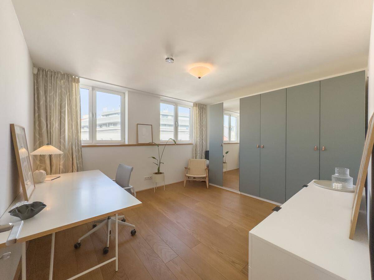 Helles Arbeitszimmer mit Holzfußboden, großen Fenstern und integrierten Schränken für Stauraum.