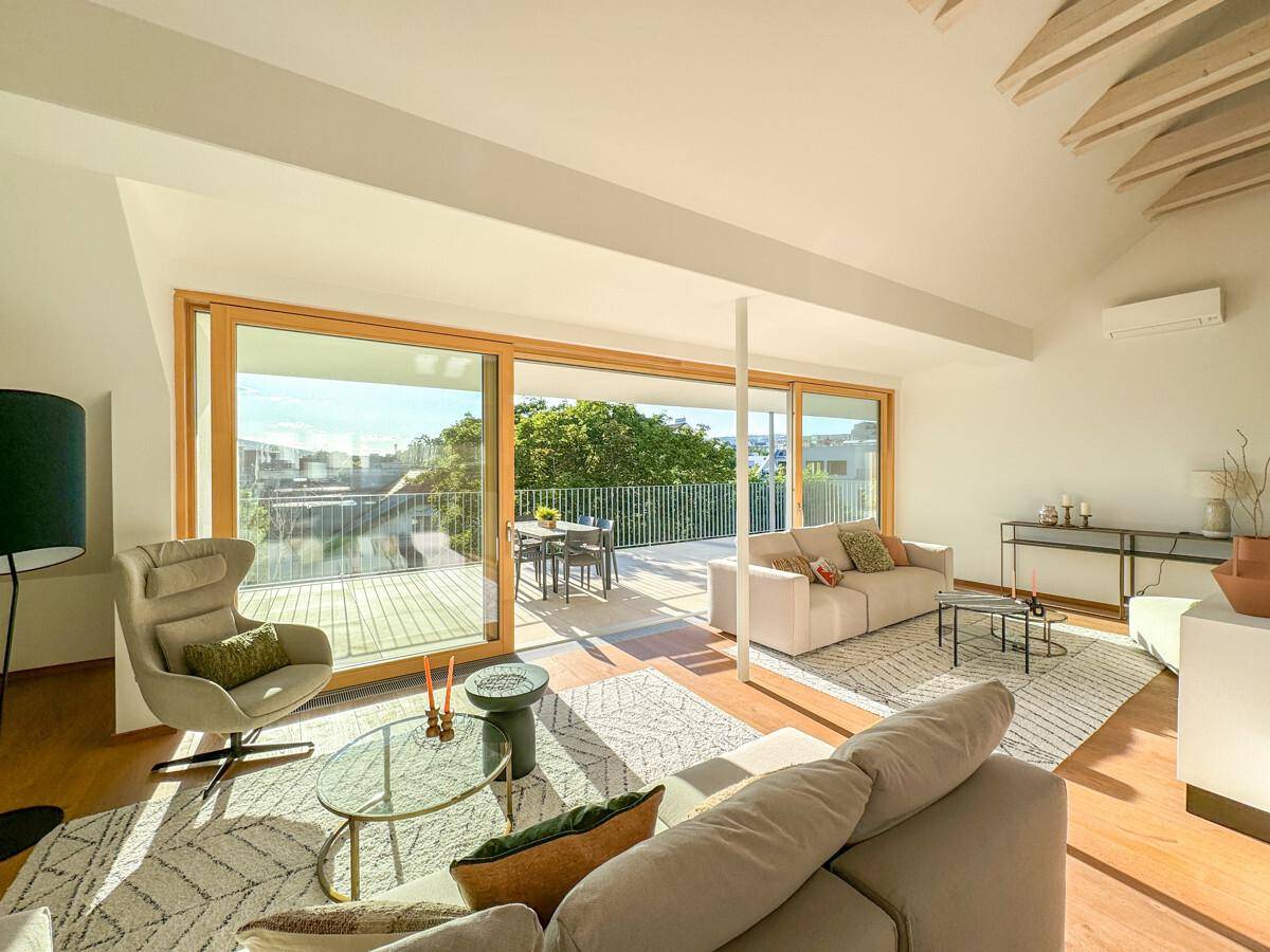 Helles Wohnzimmer mit großen Schiebetüren, die zu einer geräumigen Terrasse führen und viel Tageslicht hereinlassen.