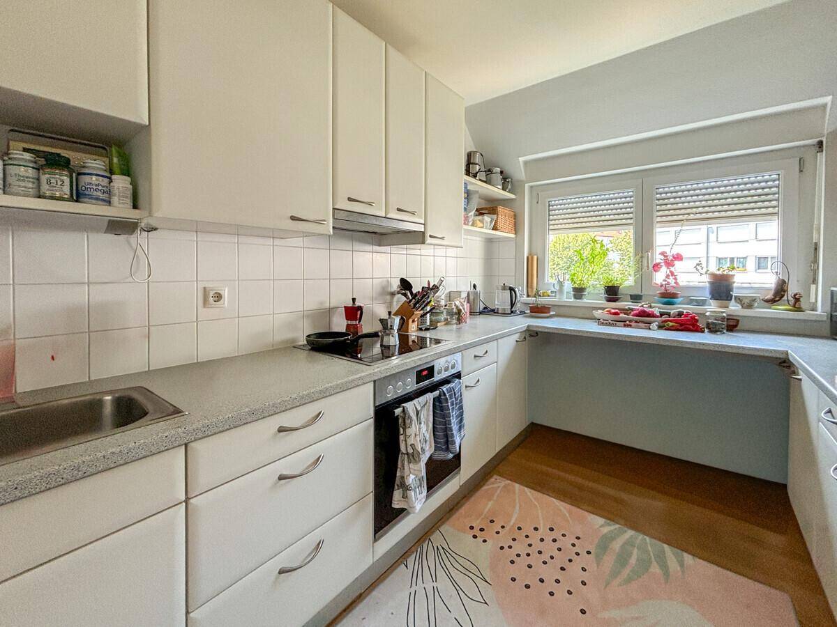 Funktionale Küche mit weißen Schränken, Fliesenrückwand und Fenster für Tageslicht.