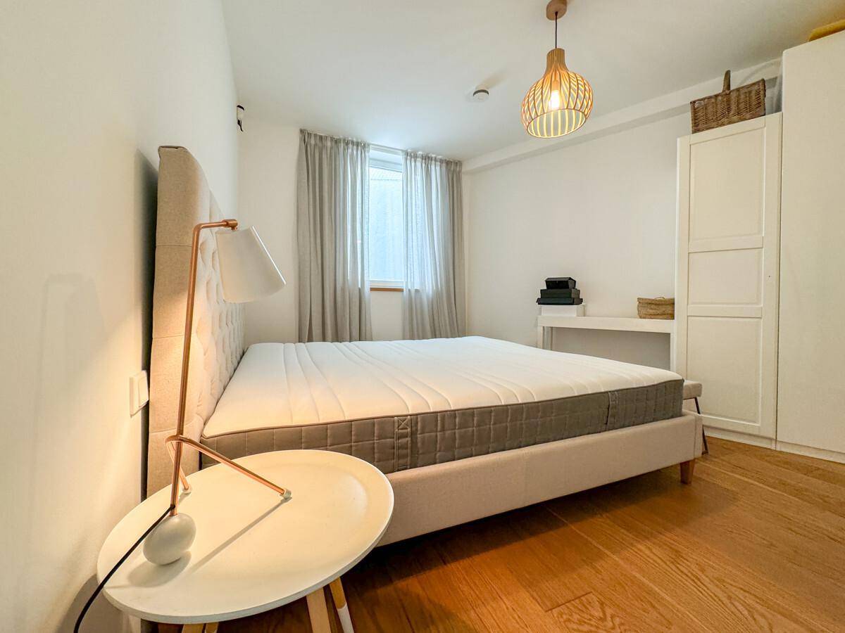 Helles Schlafzimmer mit Doppelbett, Holzboden und schlichtem, modernem Design.