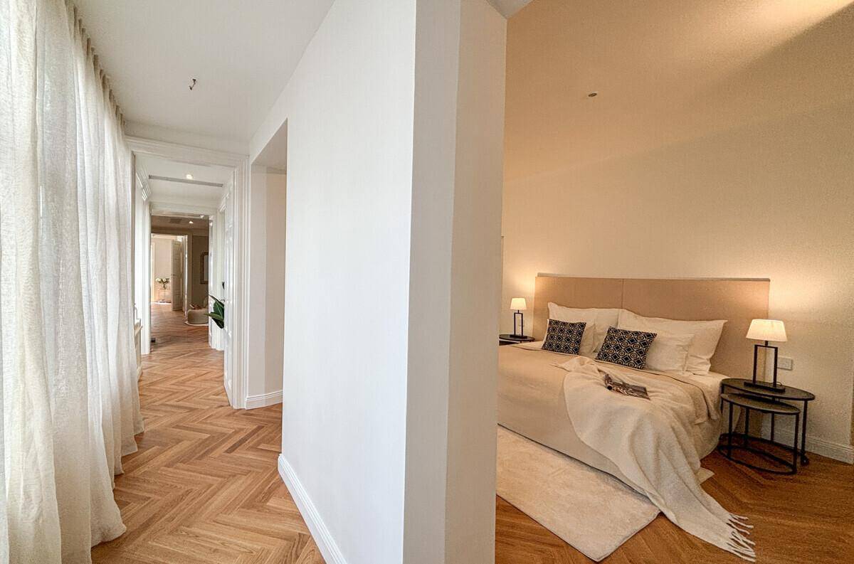 Heller Flur mit Fischgrätparkett und Vorhängen, der zu einem Schlafzimmer führt.