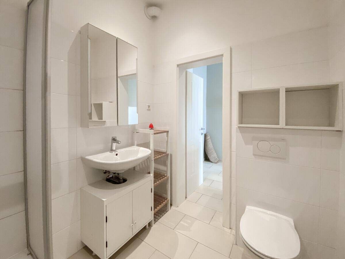 Funktionales Badezimmer mit WC, Waschbecken, Spiegelschrank und weißen Fliesen.