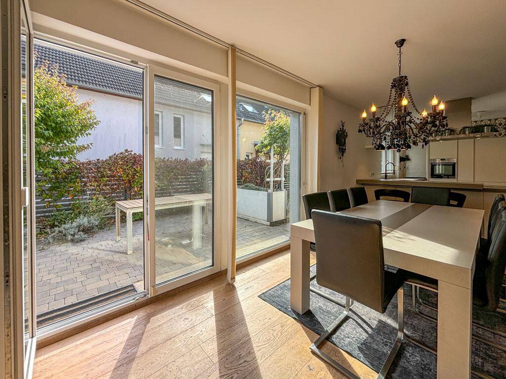 Essbereich mit großen Schiebetüren, die zur gepflasterten Terrasse und in den Garten führen.