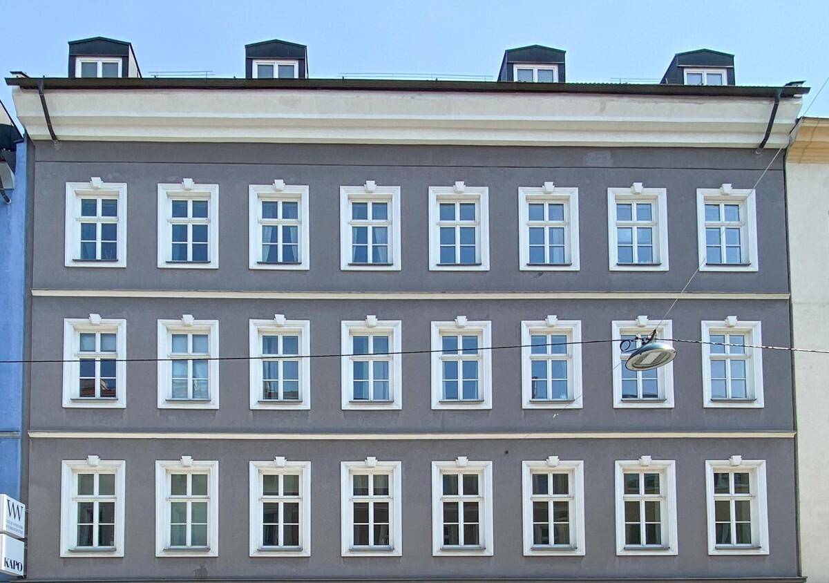 Graue Gebäudefassade mit vielen weißen Fenstern und Dachgauben, die eine klassische Architektur zeigt.