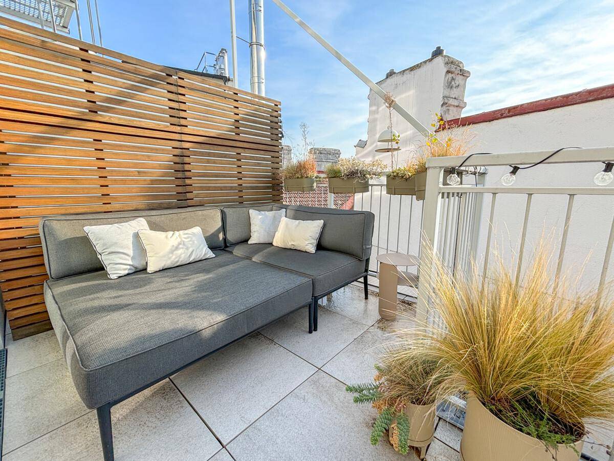 Gemütlicher Lounge-Bereich auf der Dachterrasse mit bequemen Möbeln und Holzelementen für Entspannung.