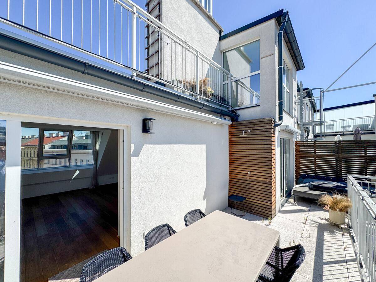 Sonniger Außenbereich mit Esstisch und Stühlen, ideal für Mahlzeiten im Freien mit Stadtblick.