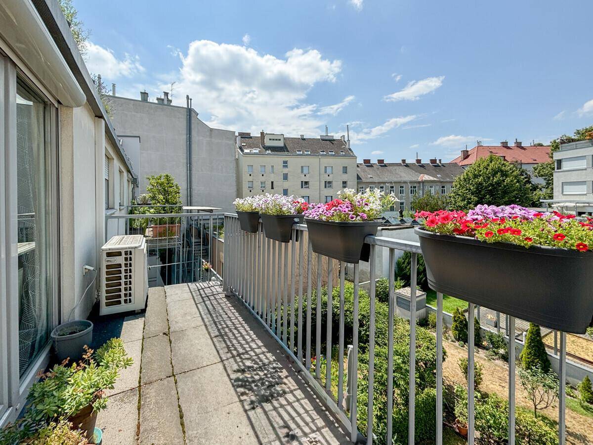 Balkon mit Blumenkästen und Klimaanlage, bietet einen Blick auf grüne Gärten.