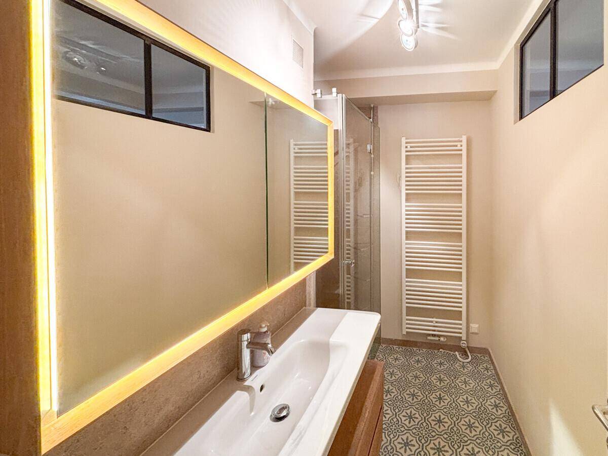 Modernes Badezimmer mit begehbarer Dusche, stilvollen Fliesen und beheiztem Handtuchhalter.