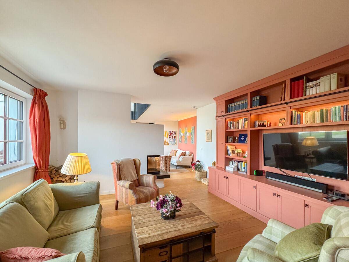Wohnzimmer mit großer, eingebauter Bücherwand, Kamin und hellem Holzfußboden.