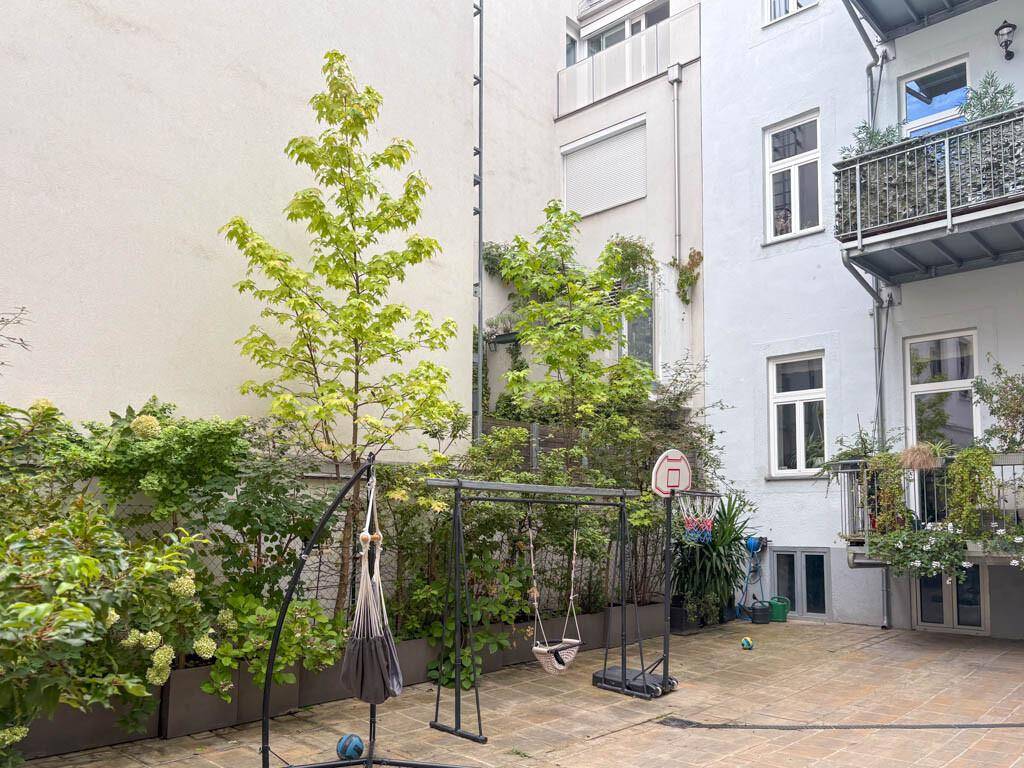 Begrünter Innenhof mit Spielgeräten und Sitzgelegenheiten zwischen den Gebäuden.