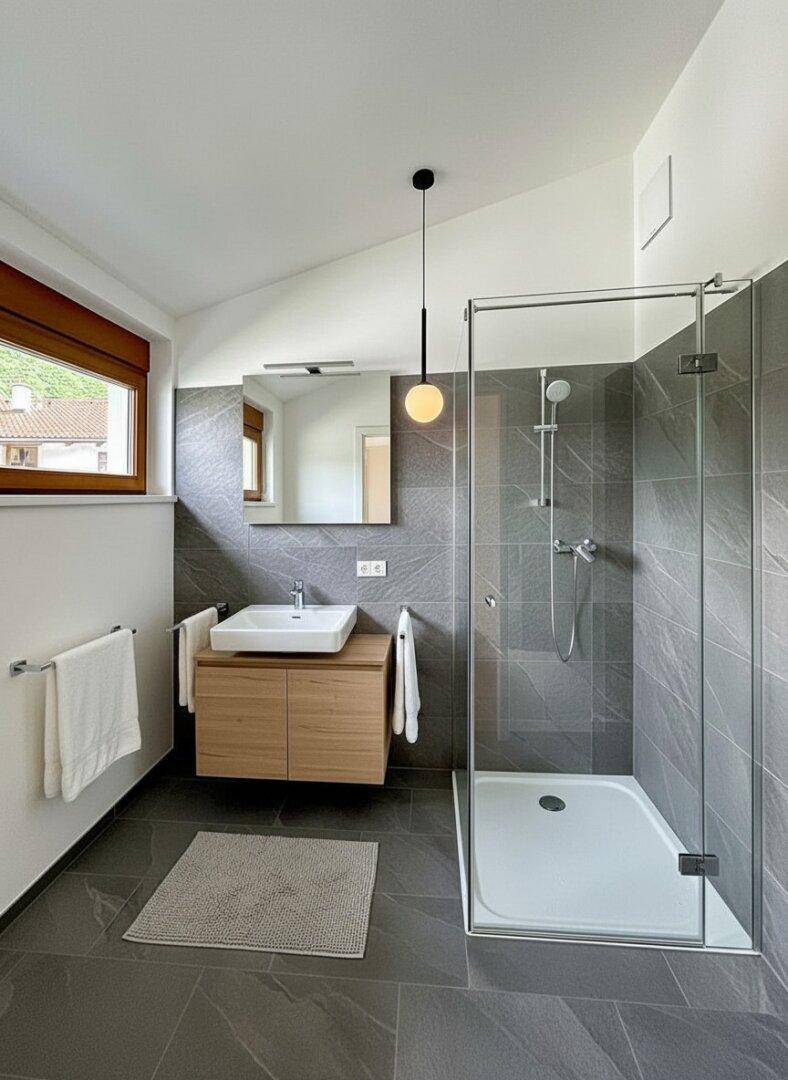 Modernes Badezimmer mit begehbarer Dusche, Einzelwaschbecken und grauen Fliesen.