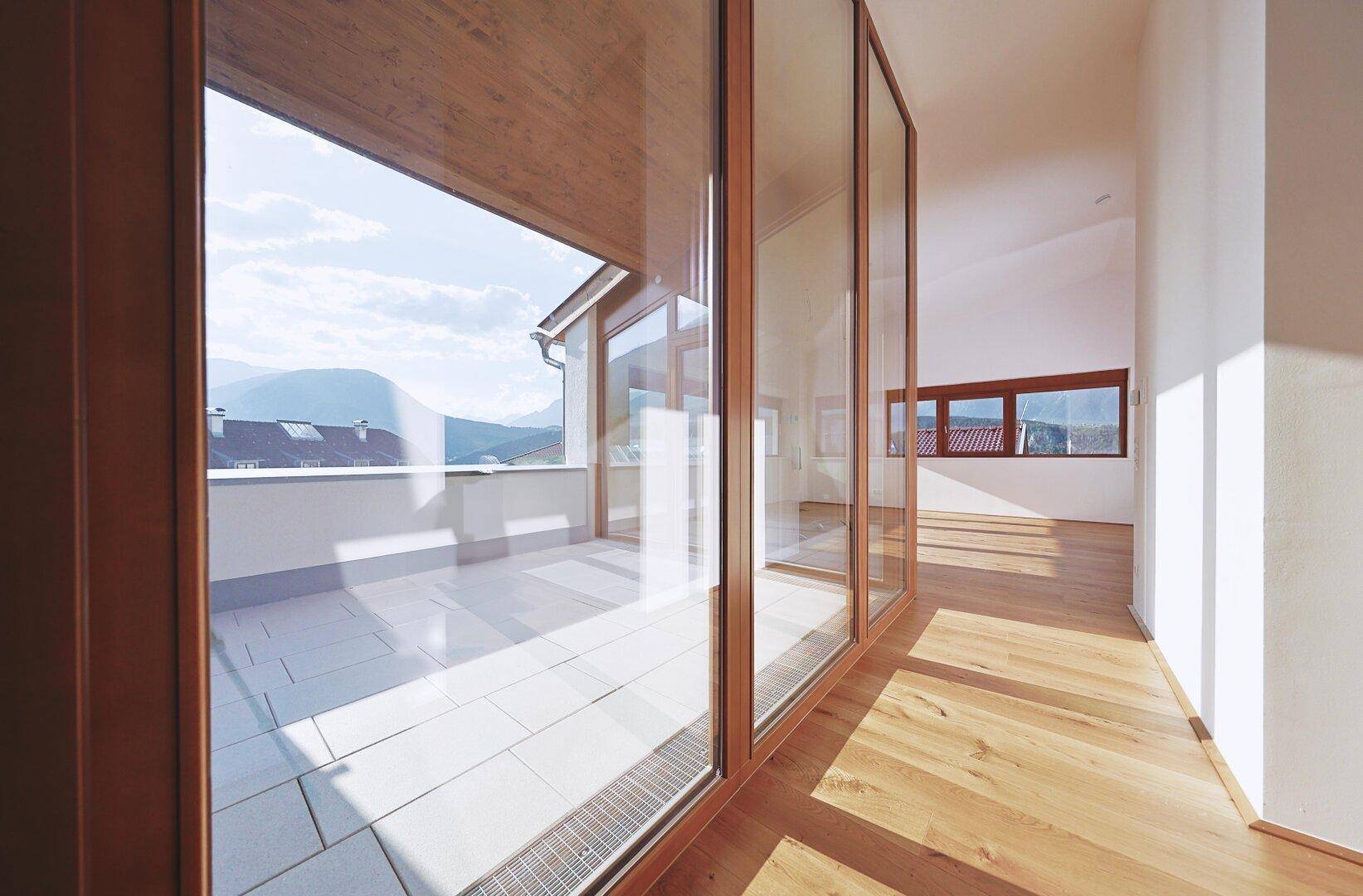 Heller Flur mit Holzboden und großen Glasfronten, die den Blick auf die Terrasse freigeben.